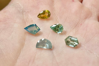 Five colorful gemstones on a person's palm