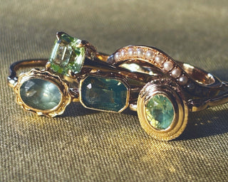 Gold ring with green gemstones on a textured fabric background